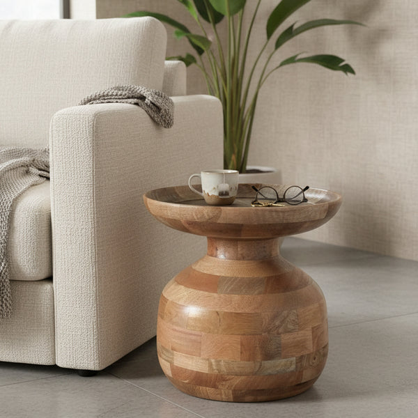 Handcrafted wooden side table with natural finish beside beige sofa, indoor plant in background