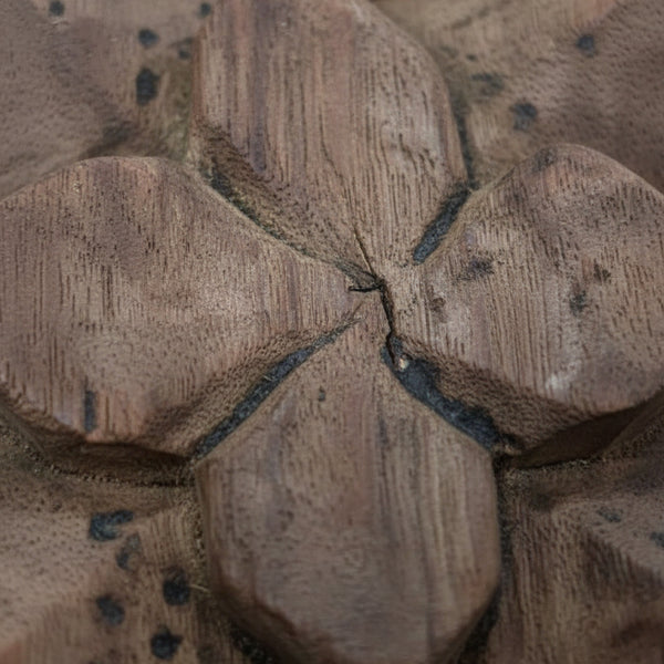 Hand-carved wooden floral motif with tribal design details and natural wood texture