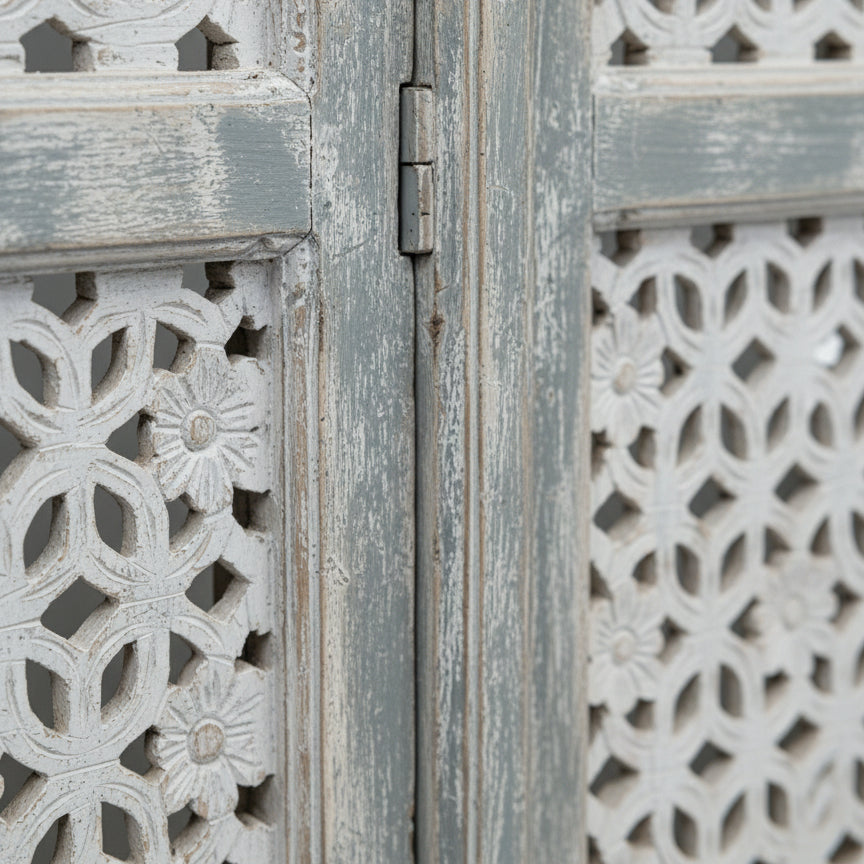 Close-up of a carved wooden room divider with floral pattern and distressed finish