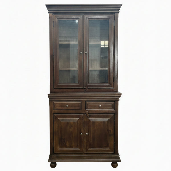Tall wooden display cabinet with glass-paneled upper doors and solid lower doors, featuring a rich dark finish and traditional handcrafted design for elegant decor.