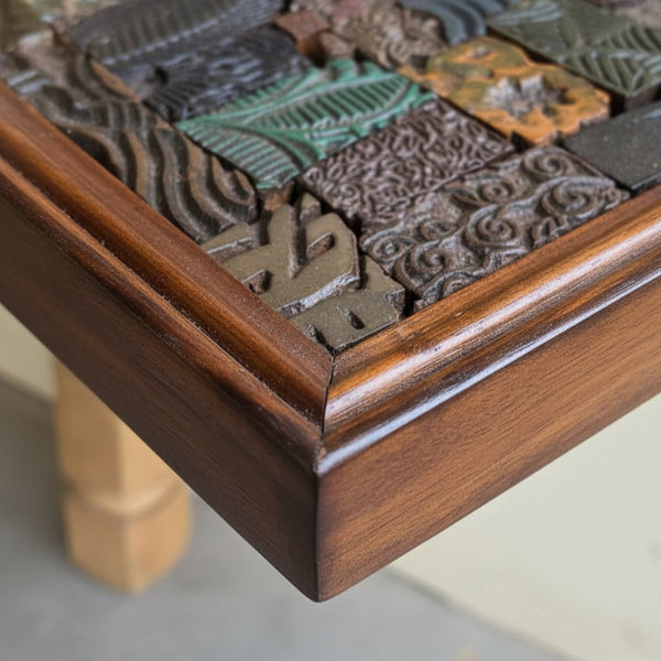 Close-up of a wooden frame featuring intricately carved mosaic tiles with tribal-inspired patterns, showcasing handcrafted decor artistry.