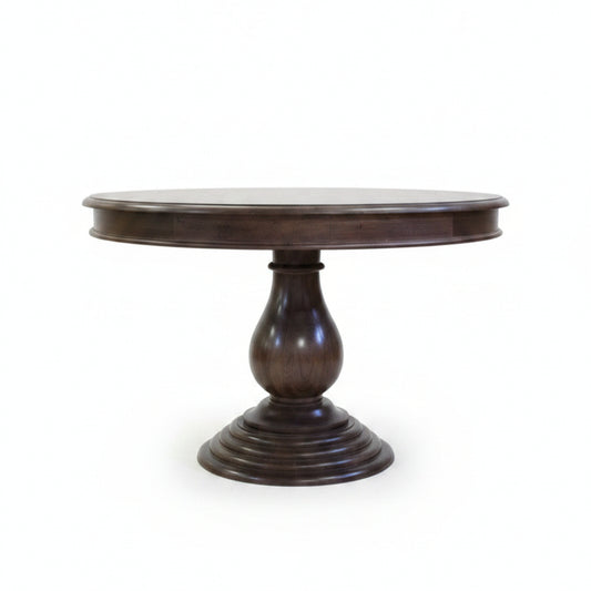 Elegant round wooden dining table with a polished dark finish, featuring a sturdy carved pedestal base, reflecting handcrafted tribal decor artistry.
