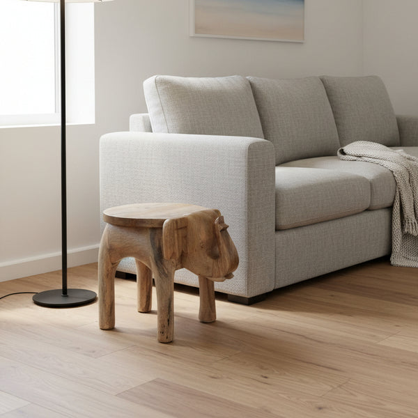Handcrafted wooden elephant stool in modern living room with light gray sofa
