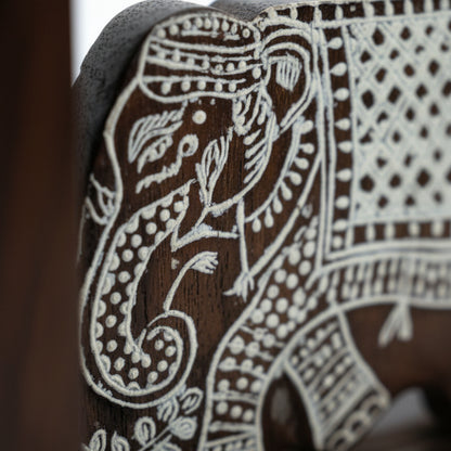 Handcrafted wooden elephant figurine with intricate tribal white carvings