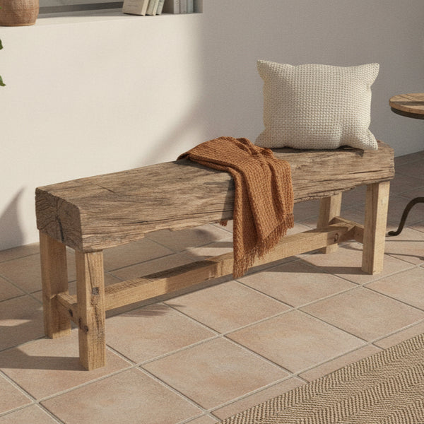Rustic wooden bench with a natural timber finish, adorned with a textured cushion and a warm brown throw, showcasing handcrafted tribal-inspired decor.