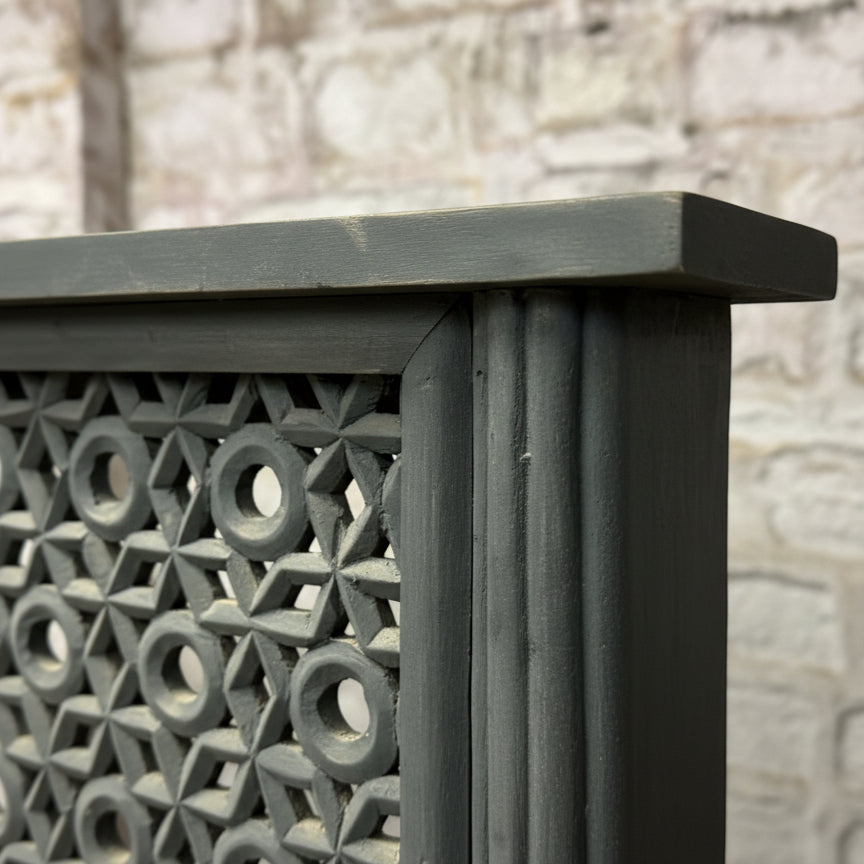 Hand-carved wooden panel with geometric tribal pattern and dark finish, close-up