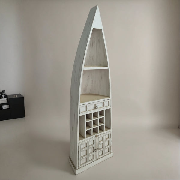 Tall wooden display unit shaped like a boat with open shelves, small drawers, and a wine rack, featuring a rustic white finish suitable for tribal handicraft decor.