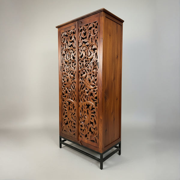 Hand-carved wooden cabinet with intricate floral patterns on doors, tribal decor style