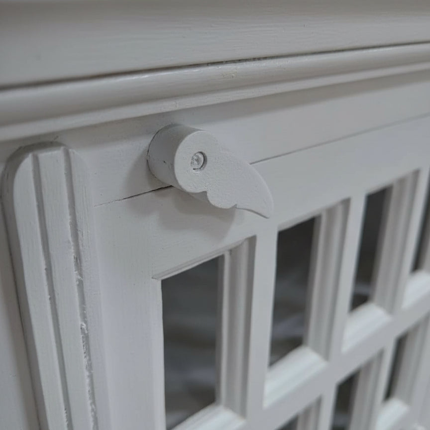 Handcrafted white wooden cabinet with glass panels and carved latch detail