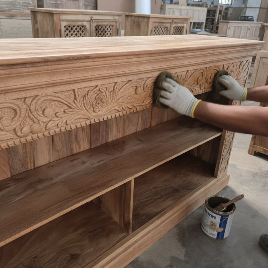 Artisan polishing a carved wooden sideboard with intricate tribal floral designs