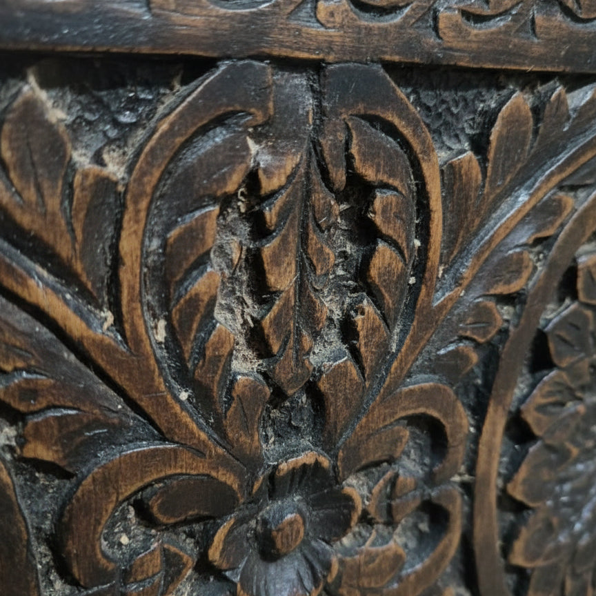 Close-up of hand-carved wooden tribal floral pattern detail, rustic handicraft texture