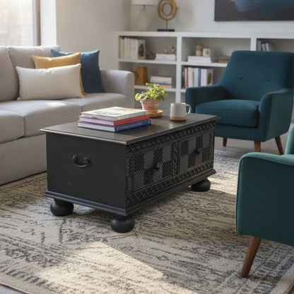 Yantra Storage Coffee Unit in dark wood with intricate carved details, placed in a cozy living room setting with books, plant, and modern furniture decor.