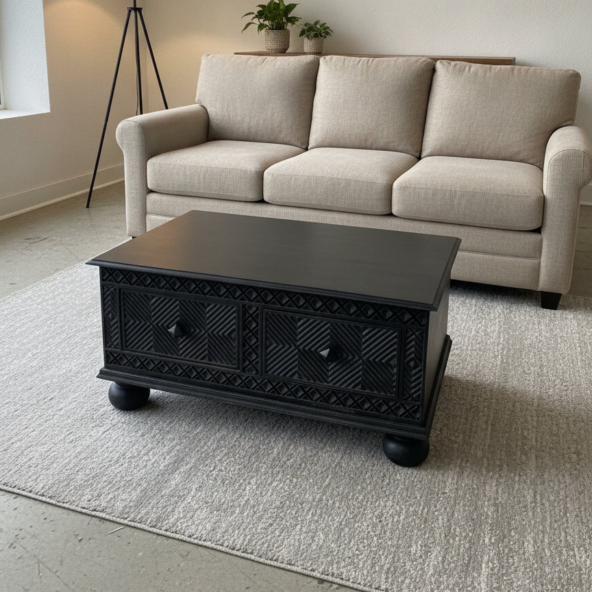 Yantra Storage Coffee Unit featuring dark wooden handcrafted design with intricate tribal patterns, placed in a modern living room with a beige sofa and neutral decor.
